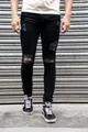 Detailed view of men's black ripped skinny jeans with distressed finish and knee holes - S / Bottoms / Black