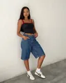 Detail view of high-waisted denim five-point shorts on model against a white wall. - S / Bottoms / Dark Blue