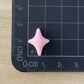 Detail view of a pink mini four-pointed star resin accessory measured on a grid ruler - Pink