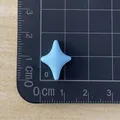 Detailed view of mini light blue four-pointed star resin accessory on measurement mat - Blue