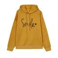 Detalle de sudadera con capucha mostaza con estampado Smile y corazón negro - Amarillo