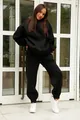Woman wearing black solid color hooded sweatshirt and matching joggers tracksuit - Black