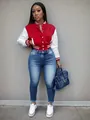 Detailed view of stylish women's red and white color-block varsity jacket and blue jeans outfit - Red