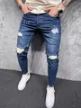 Close-up view of men's slim fit distressed blue jeans with tapered leg and white sneakers - S (28) / Bottoms / Blue