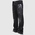Detail view of men's distressed straight-leg jeans with paint splatters and raw hem. - S / Bottoms / Black