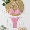 Detail view of a pink ribbed bikini set with white lacing on a straw mat background. - S / Top And Bottom / Pink