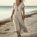 Detail view of a loose V-neck linen maxi dress on a beach, showcasing airy boho style. - Khaki