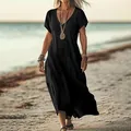 Model wearing a black loose V-neck cotton linen maxi dress walking on a sunny beach - Black