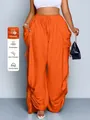 Dettaglio dei pantaloni harem arancioni a vita alta con trama in tessuto plissettato - arancio-rosso
