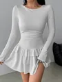 Detail view of a white long-sleeved slim fit mini dress with ruffled hem and pleated waist. - White
