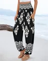 High-waisted printed harem pants with smocked waist shown on a beach setting. - S / Bottoms / Black
