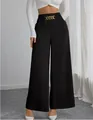 Detailed view of women's high-waisted black wide-leg trousers with gold chain decoration - S / Bottoms / Black