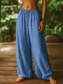 Detailed view of blue linen wide-leg pants worn by a model in a lush tropical setting - S / Bottoms / Sky Blue