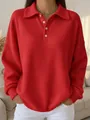 Detail shot of a vibrant red waffle-knit long-sleeved polo shirt with white buttons - S / Tops / Red