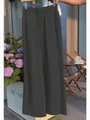 Detail view of charcoal grey pleated wide-leg trousers in a sunny outdoor cafe setting - S / Bottoms / Black