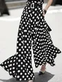 Detail view of high-waisted polka dot wide-leg trousers showing dynamic movement and fit - S / Bottoms / Black