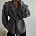 Detalle de un blazer gris con hombreras y detalle de cinturón anudado en la cintura - S / Tops / Gris