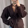 Detalle de una elegante americana marrón oscuro con lazo en la cintura y solapa. - Marrón Rojo