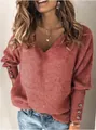 Dettaglio di un maglione in maglia a coste corallo con scollo a V e polsini con bottoni decorativi - rosso mattone
