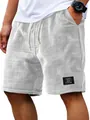 Detailed close-up of waffle texture fabric and decorative patch on men's casual shorts - M / Bottoms / White
