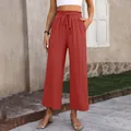 Close-up detail of women's red high-waisted loose cotton linen wide-leg pants in outdoor setting - Orange Red