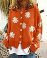 Detailansicht der orangefarbenen Strickjacke mit weißen Gänseblümchen-Stickereien. - Orange