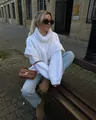 Woman wearing a chunky white knit turtleneck sweater in a European street style setting - S / White