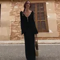 Full-length view of a black knitted long sleeve beach cover-up dress on a model outdoors. - S / Top And Bottom / Black
