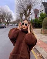 Woman wearing a chunky brown oversized turtleneck knit sweater in an outdoor street setting - Chestnut