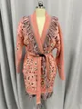 Detailed front view of a pink boho knit cardigan featuring fringe trim and jacquard pattern. - S / Tops / Watermelon red