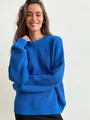 Close-up detail of a vibrant blue crew neck oversized knit sweater on a smiling model - Sapphire Blue