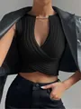 Detailed view of black slim-fit cross knit top with elegant gold chain neckline decoration. - S / Tops / Black
