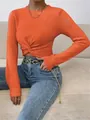 Detailed shot of an orange slim-fit crew neck knitted sweater featuring a stylish front twist - S / Tops / Orange
