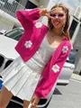 Vibrant pink knitted cardigan with white daisy flower appliques worn by a model outdoor - S / Tops / Rose Red