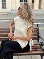 Detail of white knit vest featuring black contrast stitching and side bow ties outdoors - S / Tops / White