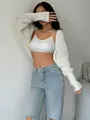 Detail of a white knit cropped shrug styled with a white camisole and blue jeans. - S / Tops / White