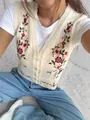 Close-up detail of cream knit sweater vest with colorful floral embroidery and V-neck - S / Tops / Apricot