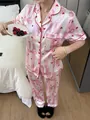 Close-up detail of a pink striped pajama set with bow and heart patterns on a model - S / Top And Bottom / Pink Striped Bowknot