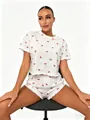 Detail of a white 100% cotton pajama set featuring red cherry prints and ruffled edges - S / Top And Bottom / Cherry