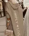 Detailansicht eines beigen Kapuzenstrickmantels mit Simply Live-Aufdruck auf dem Rücken - Khaki