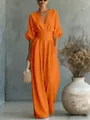 Close-up detail of an elegant orange V-neck wide-leg jumpsuit with a cinched waist design - Orange