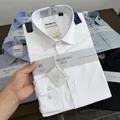 Close-up detail of a folded white mulberry silk blend men's shirt with product labels. - 38 / Tops / White