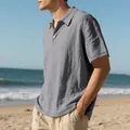 Casual men's grey linen polo shirt with short sleeves worn on a sunny summer beach - Gray