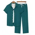 Detail of men's dark teal pleated two-piece set featuring short sleeve shirt and trousers - Dark Green