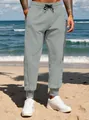 Men's grey casual sweatpants with tapered cuffs shown in a sunny beach environment. - S / Bottoms / Light Gray