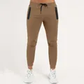 Close-up of men's brown slim-fit joggers with vertical zipper pockets and elastic drawstring. - S / Bottoms / Khaki