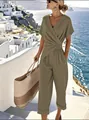 Femme élégante en combinaison croisée kaki avec col en V sur une terrasse vue sur la mer - S / Haut Et Bas / Kaki