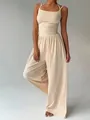 Detail view of a beige summer jumpsuit featuring a wrap-waist and flowing wide-leg cut. - Apricot