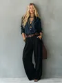 Detailed view of elegant high-waisted wide-leg black trousers with a fluid drape. - S / Bottoms / Black