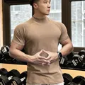 Detailed shot of men's athletic high-neck gym t-shirt showing fabric texture and fit - M / Tops / High Neck / Camel Gray